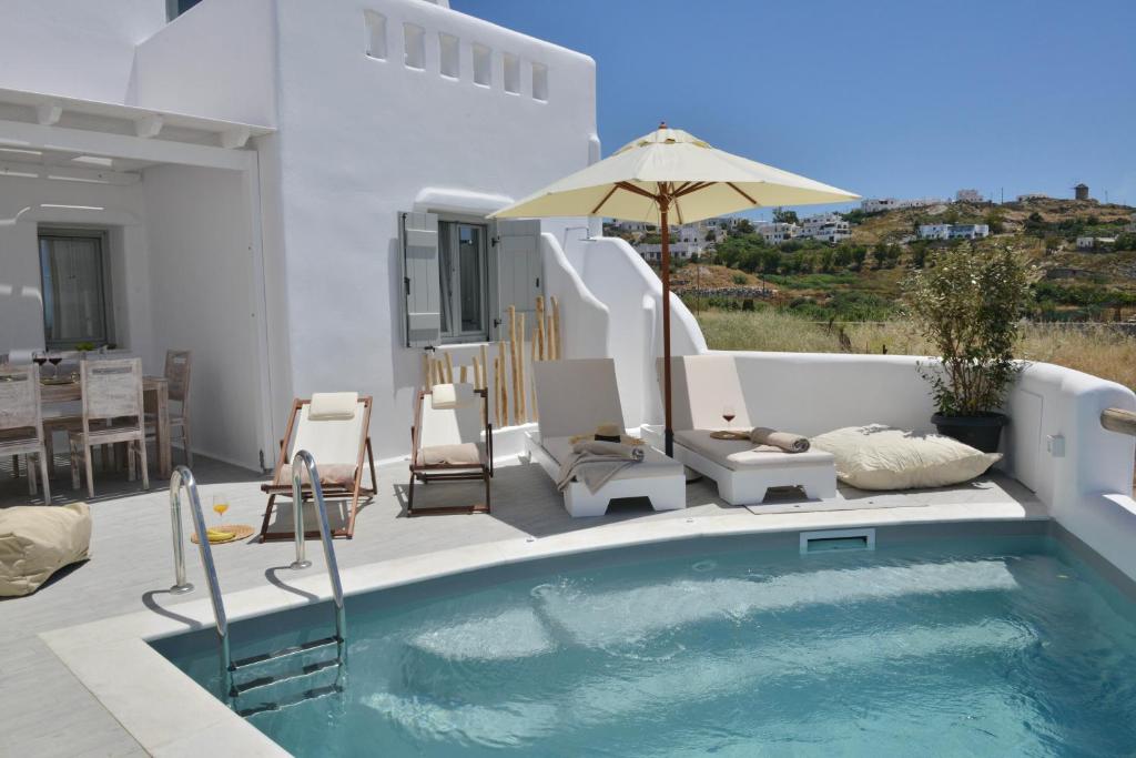 a swimming pool with chairs and an umbrella on a patio at Villa kleio Naxian album with private pool in Glinado Naxos