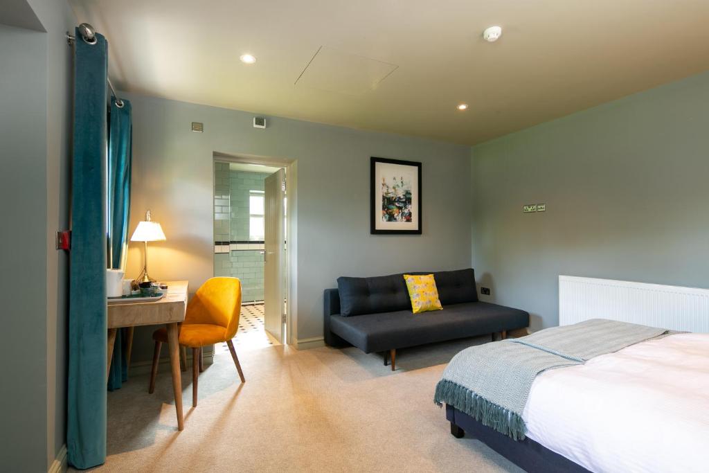 1 dormitorio con cama, escritorio y silla en The Cowdray Arms, en Haywards Heath