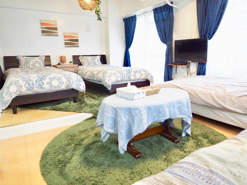 um quarto com três camas e uma televisão e uma mesa em Holiday Homes TSUBOYA 301 em Naha