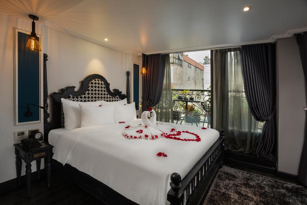 a bedroom with a bed with red rose petals on it at Hanoi Esplendor Hotel and Spa in Hanoi