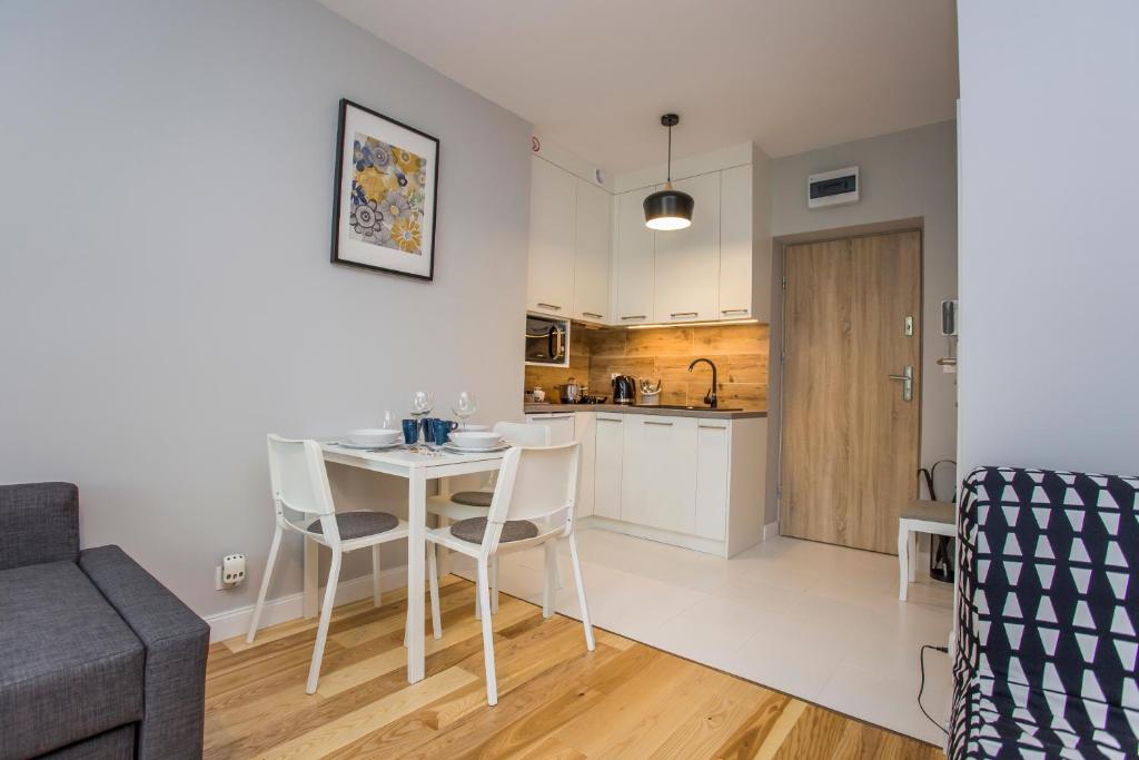 CR Uroczy Apartament w Centrum Nowy Świat 18 في بياويستوك: مطبخ وغرفة معيشة مع طاولة وكراسي