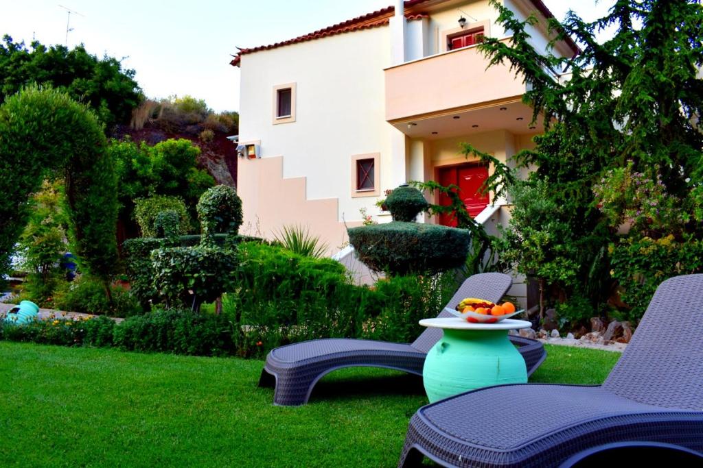 einen Garten mit 2 Stühlen und einer Schale Obst auf einem Tisch in der Unterkunft Irene's Comfort Villa in Nea Epidavros