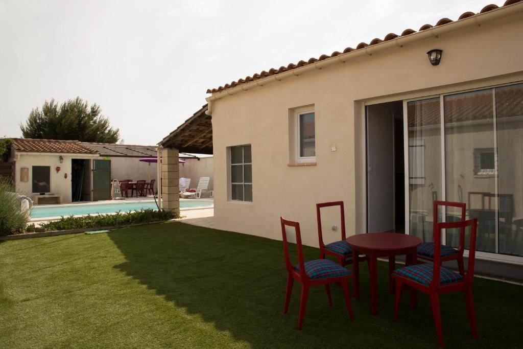 un patio con sillas rojas y una mesa en un patio en Studio l'Obrador 25 m2, vue jardin & terrasse + accès piscine, en Rieux-Minervois