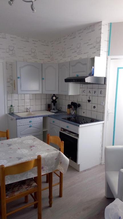 a kitchen with white cabinets and a table and a stove at FLAB &#39; DES VENTS in Le Tréport