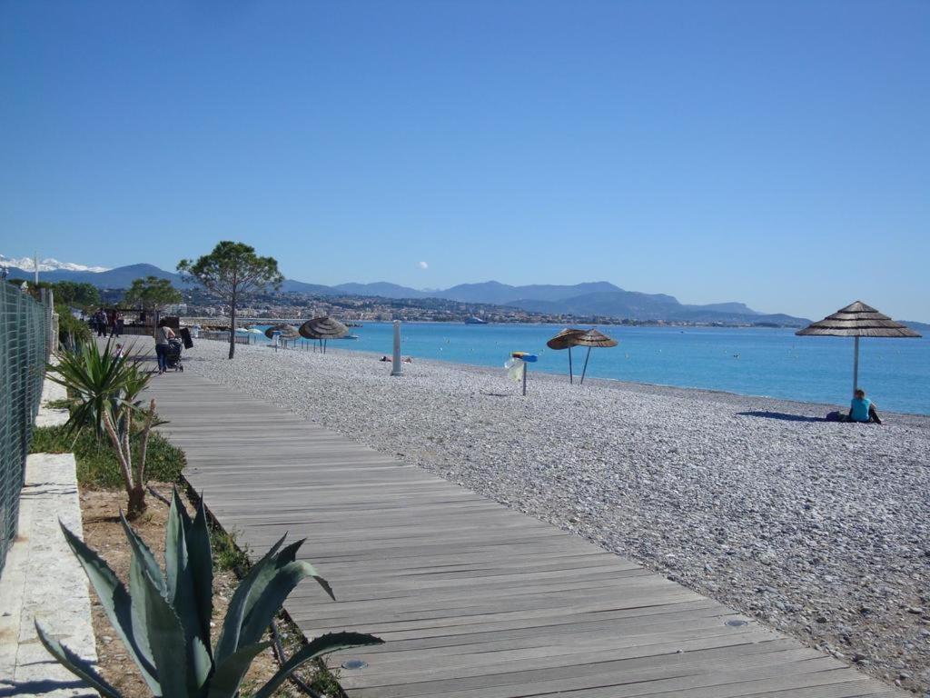 a wooden path on a beach with umbrellas and the water at bel Appartement les pieds dans l'eau in Villeneuve-Loubet
