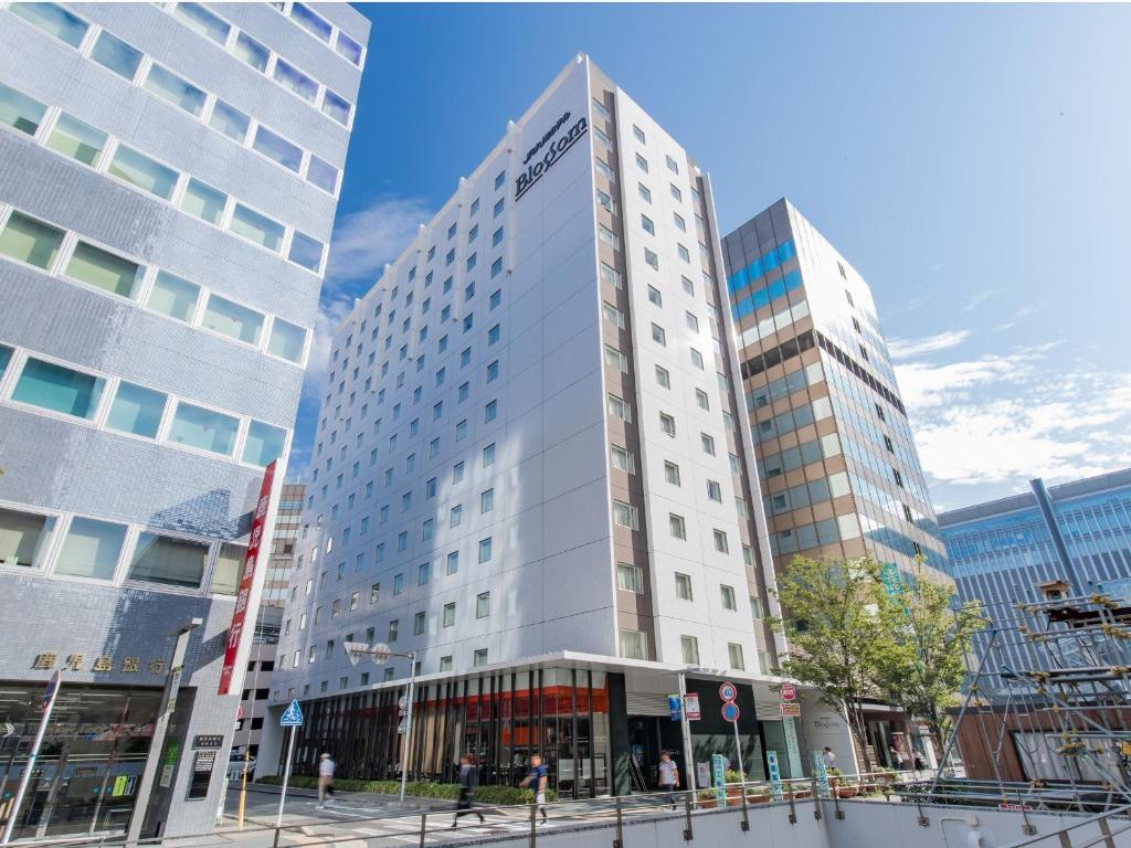 a tall white building with two tall buildings at JR Kyushu Hotel Blossom Hakata Central in Fukuoka