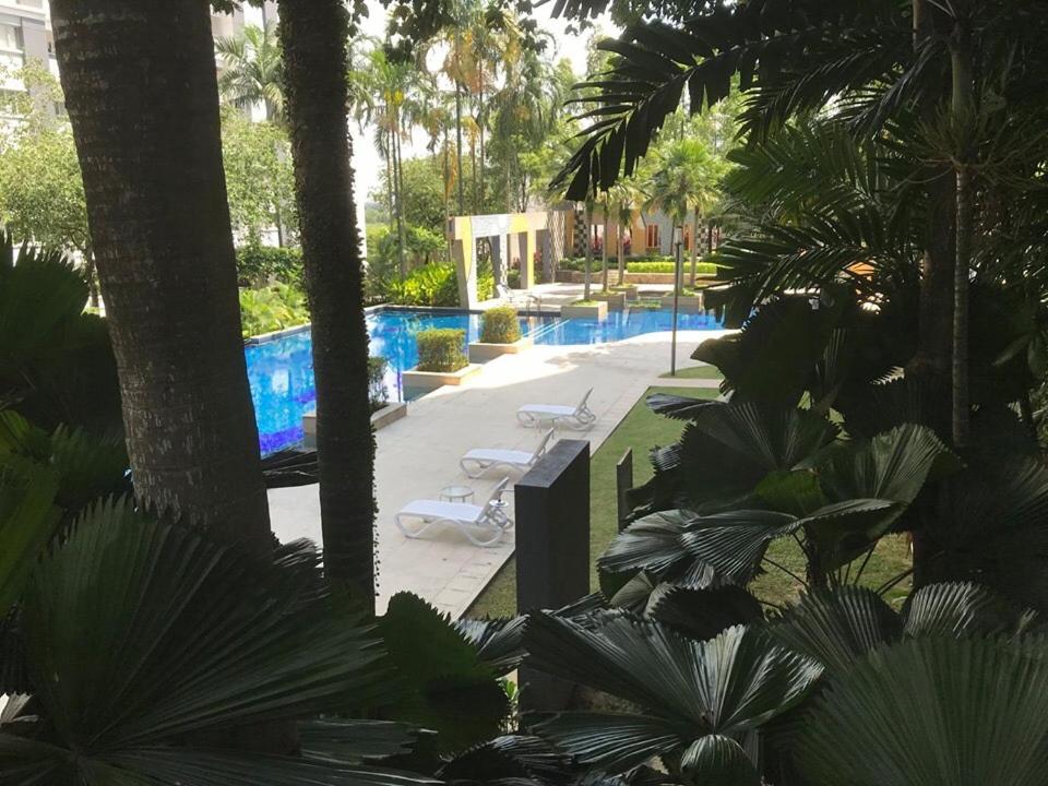 una piscina con 2 tumbonas y palmeras en Amisha Home Design & Comfortable 2 Bedrooms Apartment en Petaling Jaya