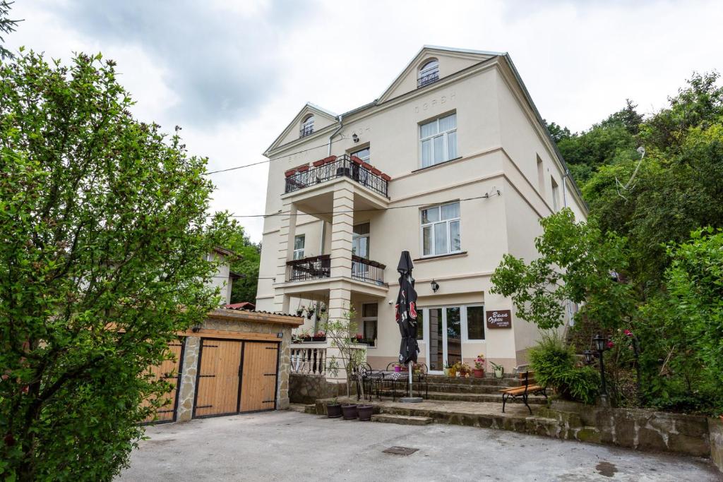 a large white house with a fence in front of it at Apartments Ozren in Soko Banja