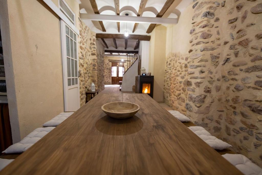duży drewniany stół w pokoju z kamienną ścianą w obiekcie Casa Rural Pradas w mieście Montanejos