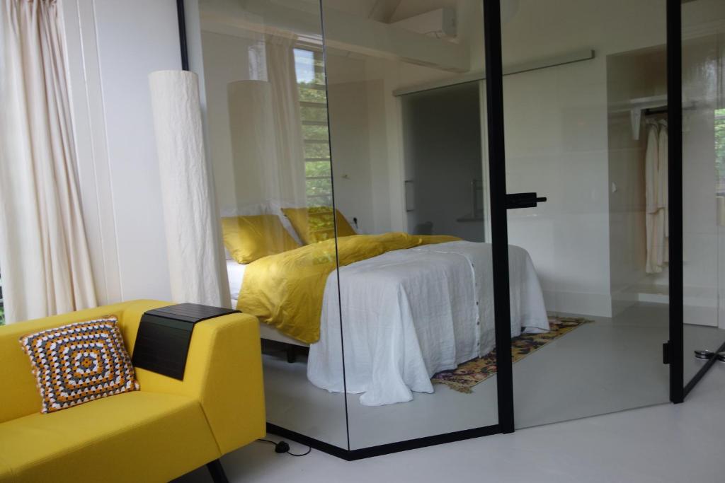 een slaapkamer met een bed en een gele bank bij B&B Achterom in Loon op Zand