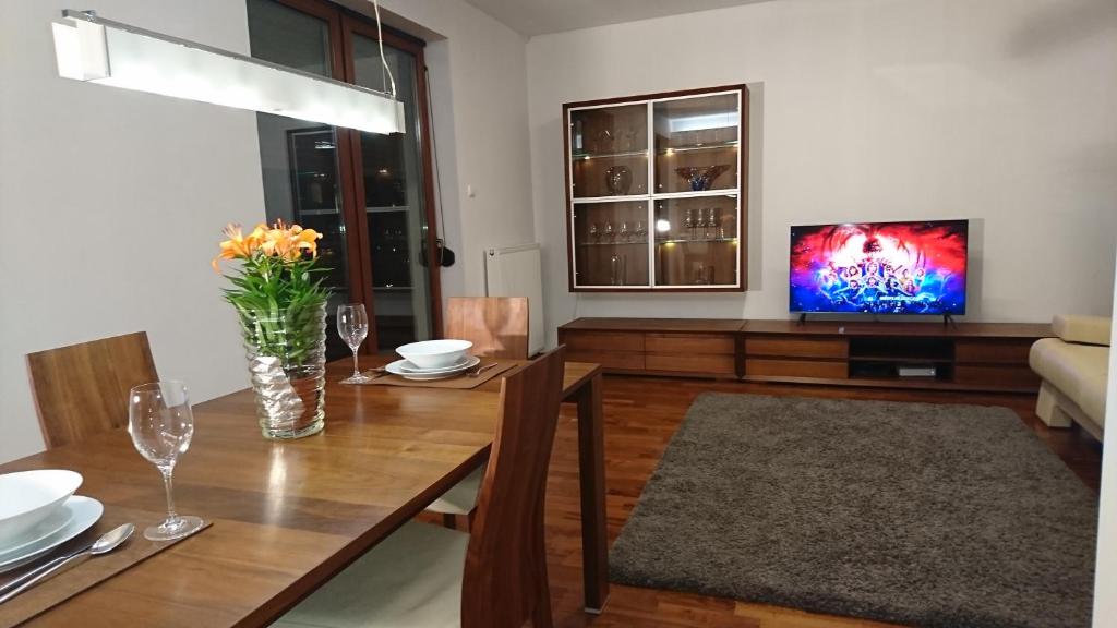 a living room with a wooden table and a television at Quiet and spacious apartment with garage option in Kraków