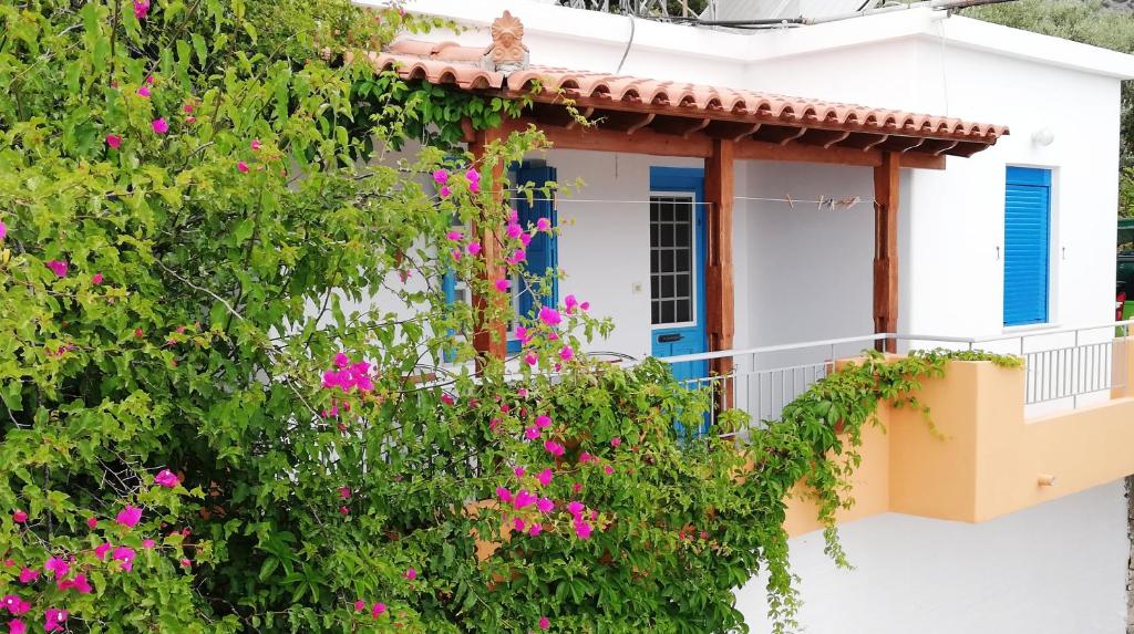 a white house with a blue door and pink flowers at Apartments Jota in Marathokampos