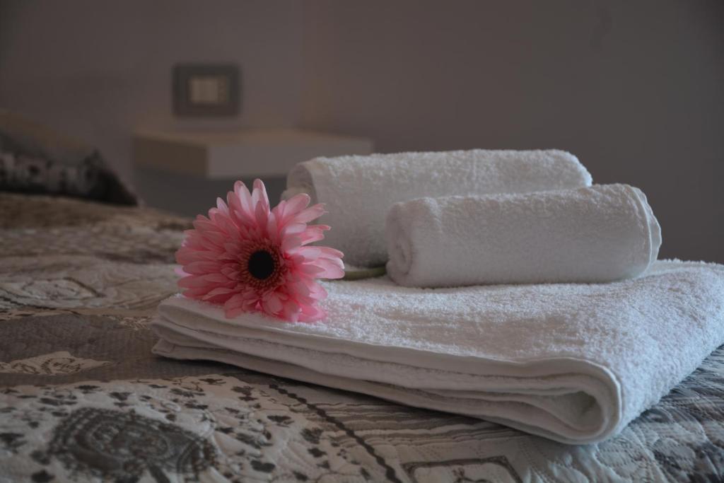 a pile of towels and a pink flower on a bed at B&B Il nido dei sogni in Castelmezzano