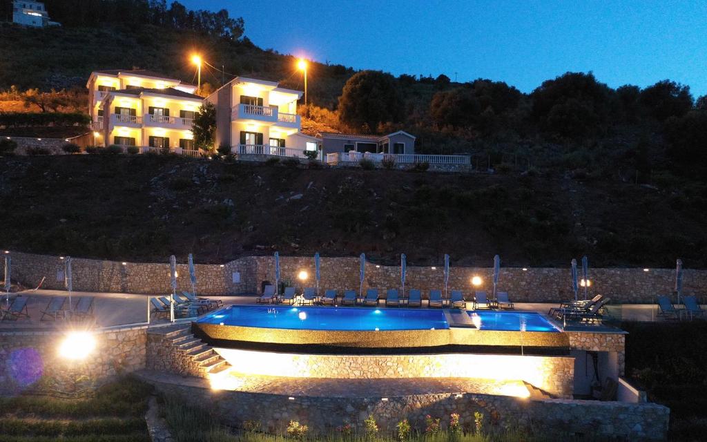 a swimming pool in front of a house at night at Blue Bay Apartments in Sivota