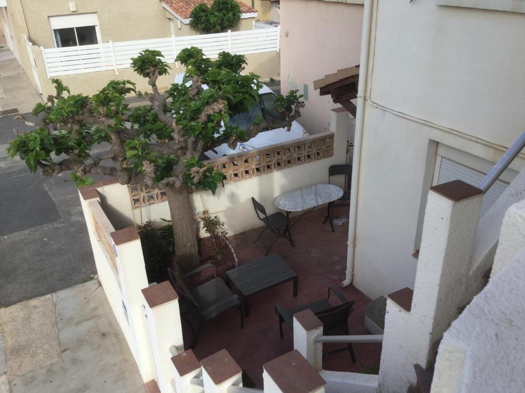 Apartamento con balcón con árbol, mesa y sillas. en Villa Magaly T4 à 50 m de la plage de Valras centre, en Valras-Plage