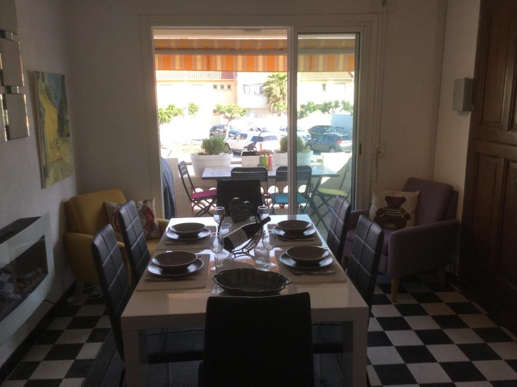 comedor con mesa y sillas y vistas a un patio en Villa Magaly T4 à 50 m de la plage de Valras centre, en Valras-Plage