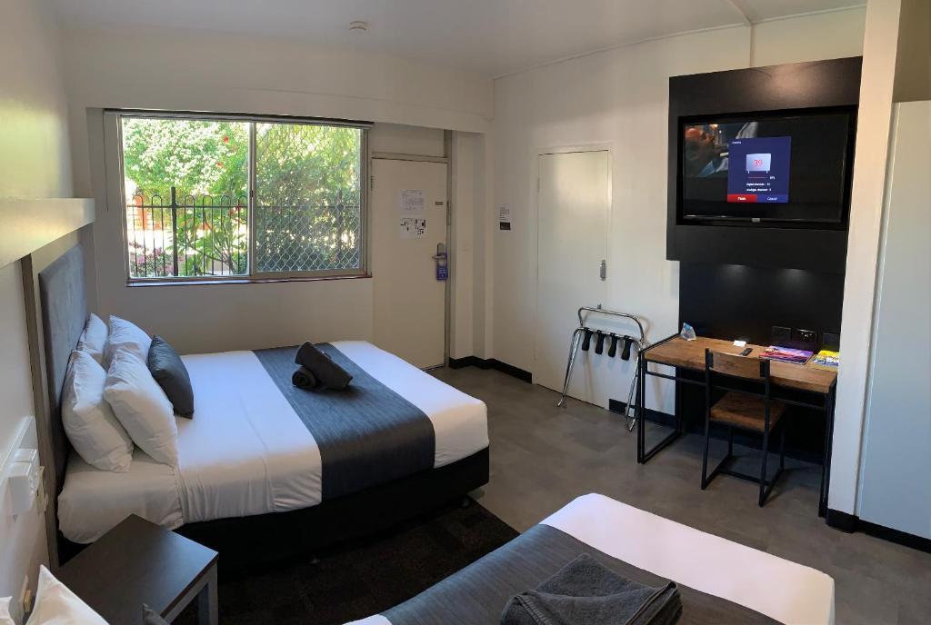 um quarto de hotel com uma cama, uma secretária e uma televisão em The Stuart Hotel-Motel em Katherine