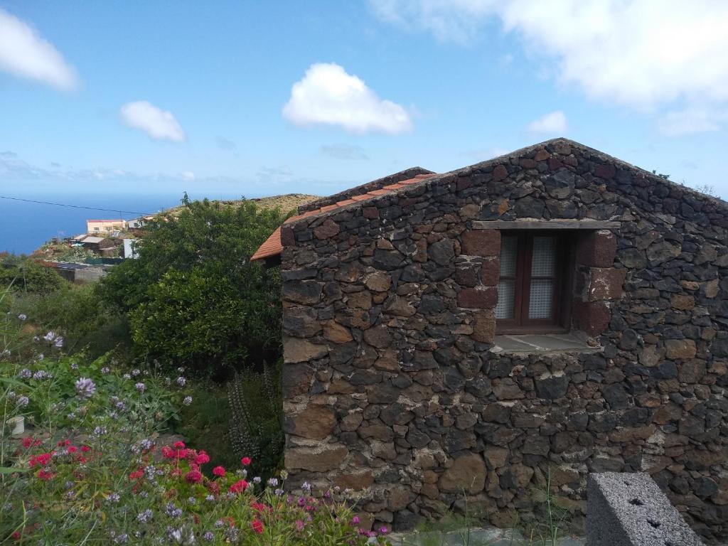 un edificio de piedra con una ventana en una colina en Casa Rural Higuera Morales, en Mocanal