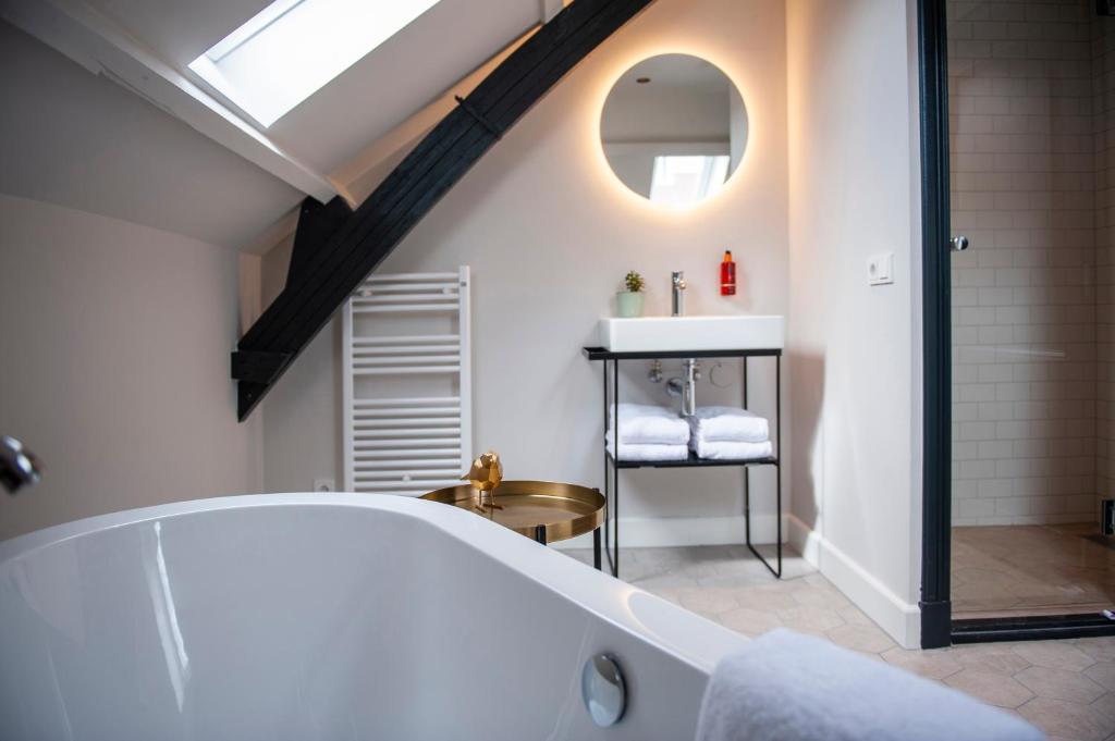een badkamer met een ligbad en een wastafel bij FINCH Boutique Hotel, downtown in Deventer