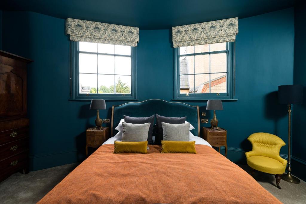 a blue bedroom with a bed and two windows at Aragon House in London