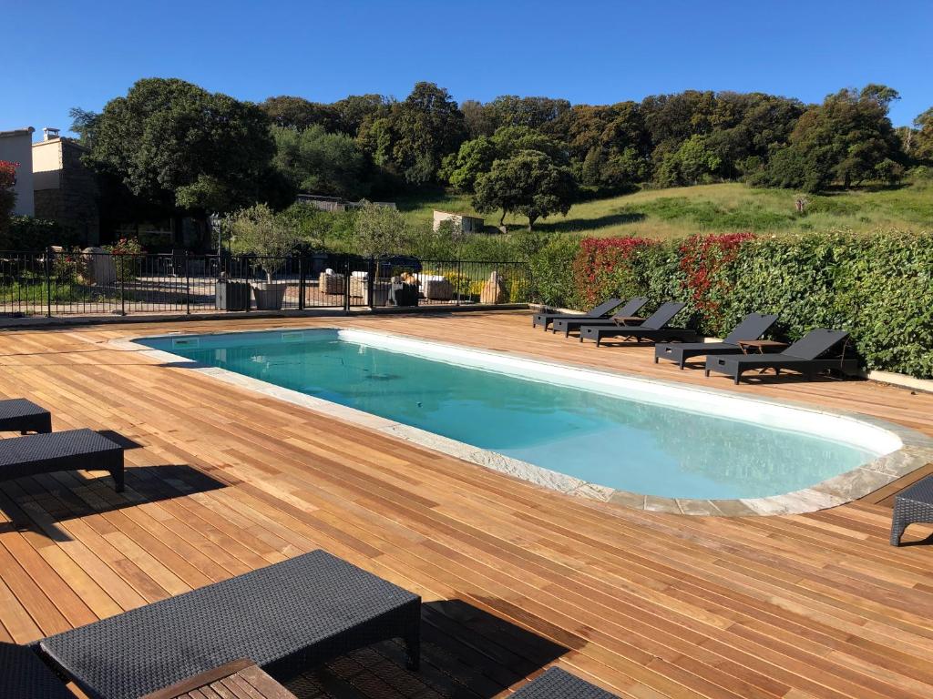 una piscina con sedie e una terrazza in legno di Hotel & Restaurant Les Bergeries d'Alata ad Alata