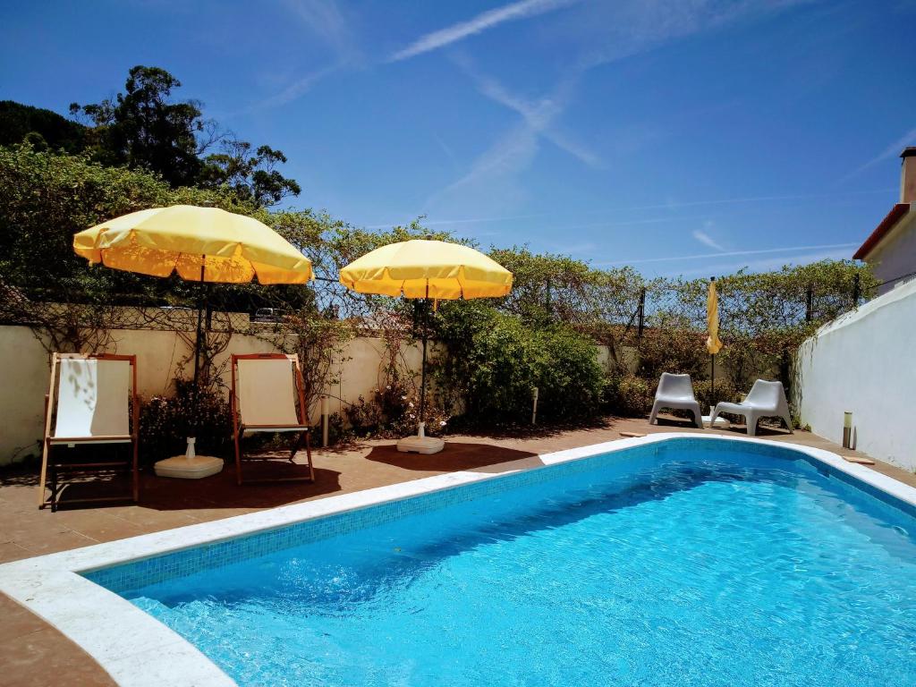 - une piscine avec 2 parasols et 2 chaises dans l'établissement Casa de Atalaia, à Palmela