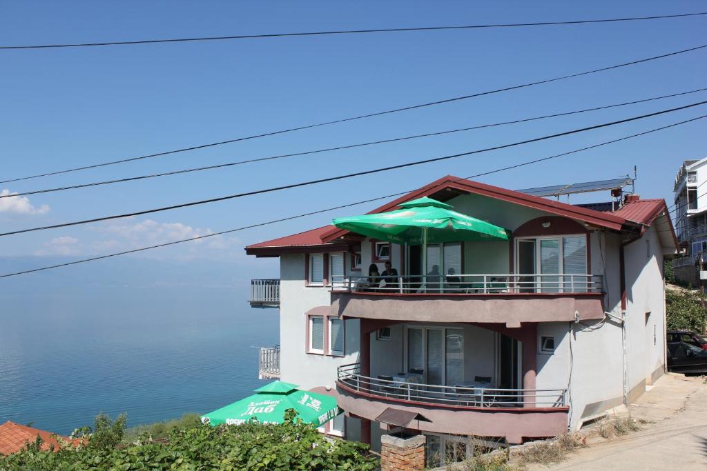 a building with a balcony with green umbrellas at Vila Idila in Ohrid