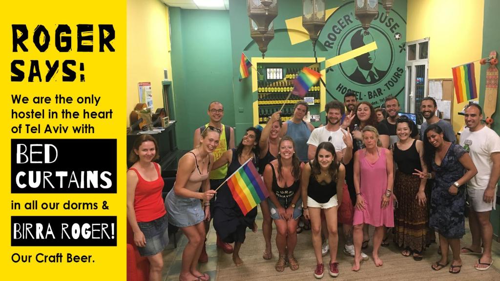 a group of people posing for a picture in front of a clock at Roger's Hostel Tel Aviv (age 18-45) in Tel Aviv