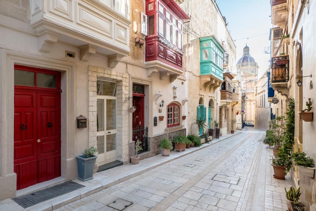 an alley with red doors in an old town at Kharmen A 1565s House with Seaviews in Birgu