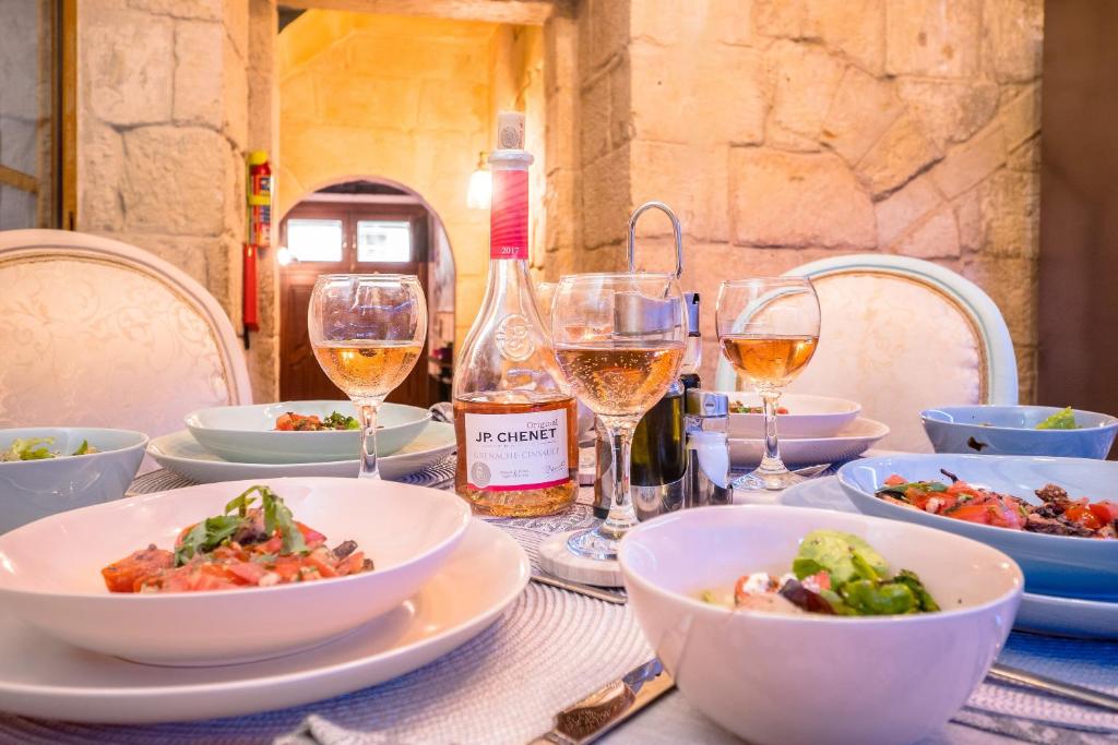 a table with plates of food and glasses of wine at Kharmen A 1565s House with Seaviews in Birgu
