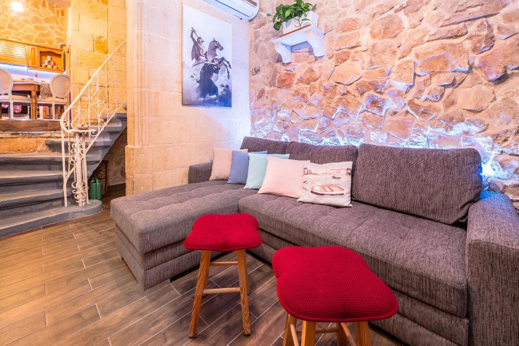 a living room with a couch and two red stools at Kharmen A 1565s House with Seaviews in Birgu
