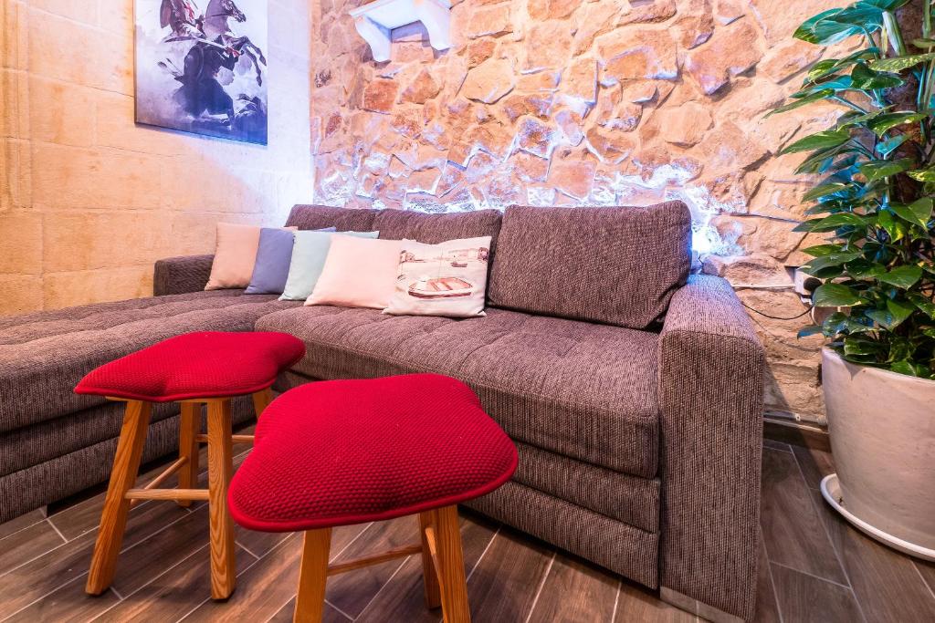 a living room with a couch and two red stools at Kharmen A 1565s House with Seaviews in Birgu