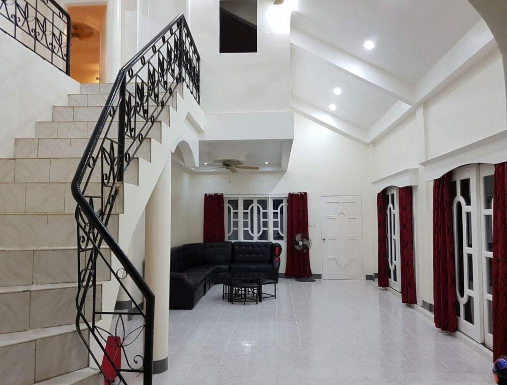 a living room with a black couch and stairs at OMG Guesthouse room for 7 in Quinawitnan