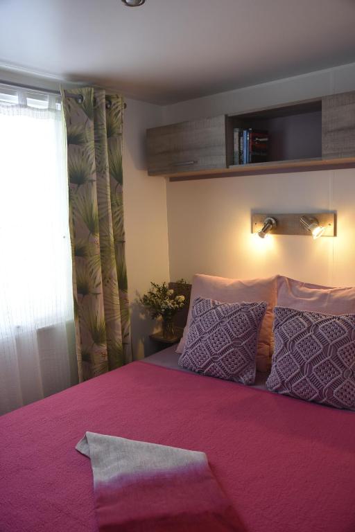 a bedroom with a pink bed with purple sheets and pillows at Sas Robrecht in Saint-Tropez