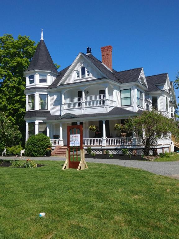 a large white house with a sign in the yard at By The River B&B in Fredericton