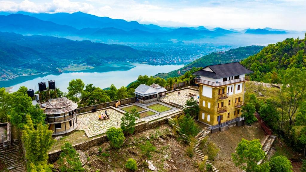 an aerial view of a building on a hill next to a lake at Pumdikot Mountain Lodge in Kāskī