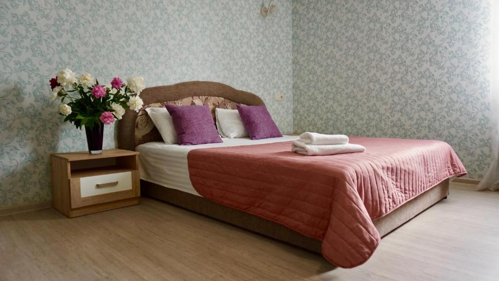 a bedroom with a bed with a vase of flowers on it at Zhuliany City Hotel in Kyiv