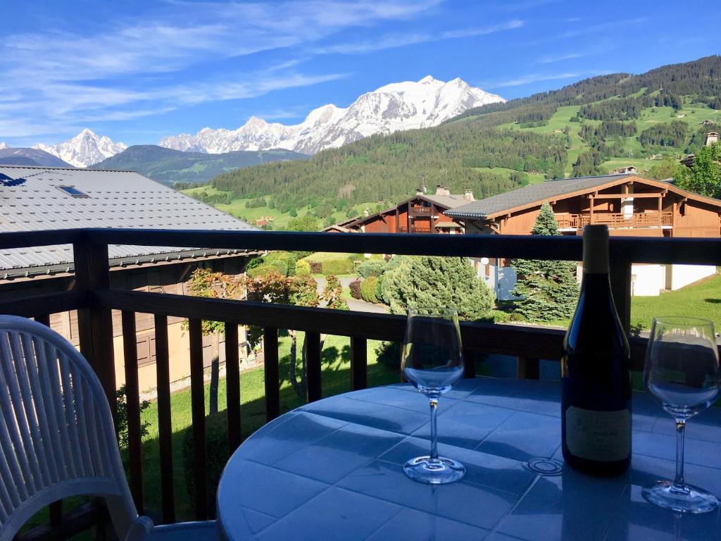 una botella de vino sentada en una mesa con dos copas en Appartement cosy et chaleureux à Megève avec vue sur le Mont Blanc, en Demi-Quartier