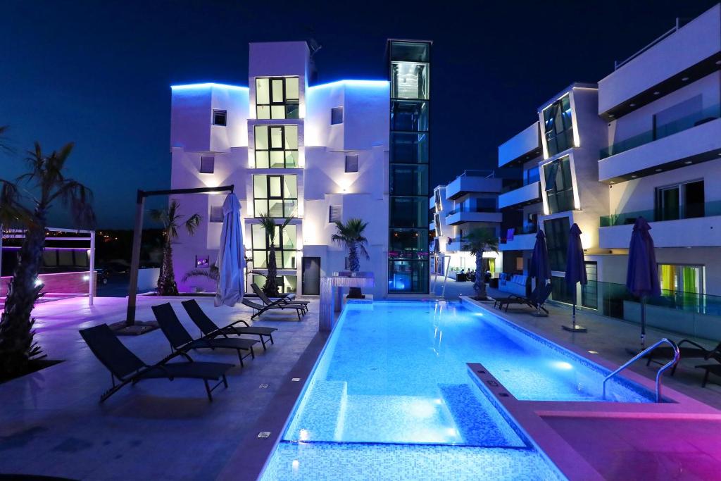 une piscine d'hôtel avec des bâtiments la nuit dans l'établissement Boutique Residence Cosmopolis 1, à Bibinje