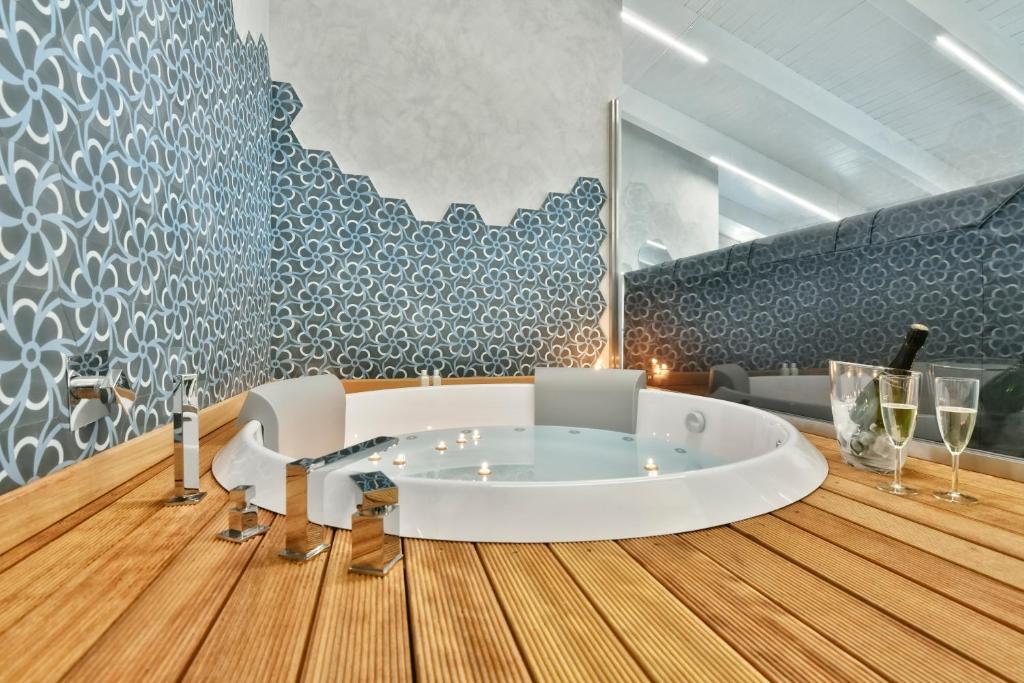 bagno con vasca bianca e pavimento in legno di Amnis suites a Santa Maria di Castellabate