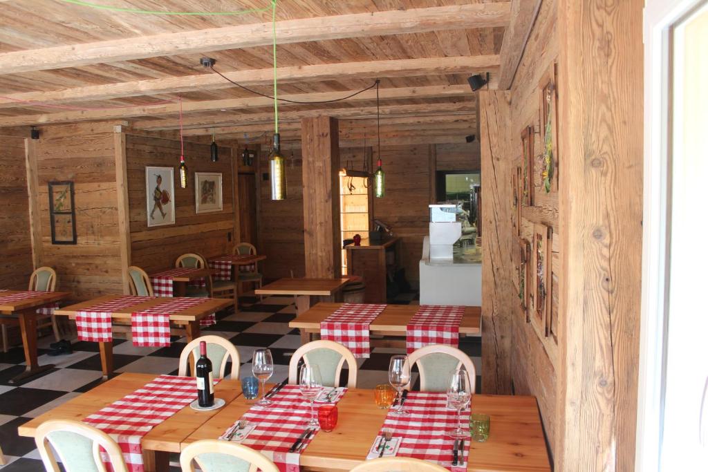 ein Restaurant mit Holztischen und roten und weißen karierten Böden in der Unterkunft Hotel Al Rom in Tschierv