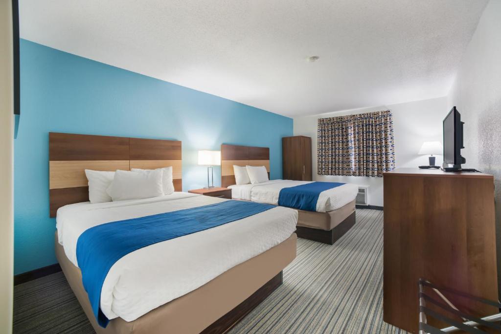 a hotel room with two beds and a flat screen tv at Ramada by Wyndham Effingham in Effingham