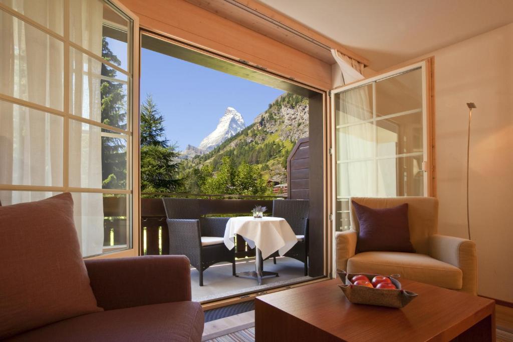 a living room with a table and a view of a mountain at Mirabeau Alpine in Zermatt