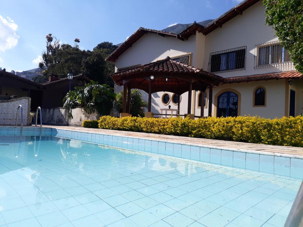 a swimming pool in front of a house at Aconchegante da Serra in Teresópolis