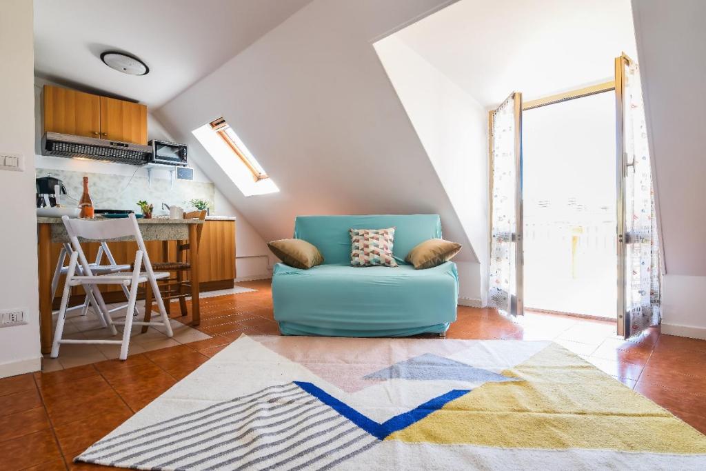 a living room with a blue chair and a kitchen at LA MANSARDINA VINTAGE in San Benedetto del Tronto