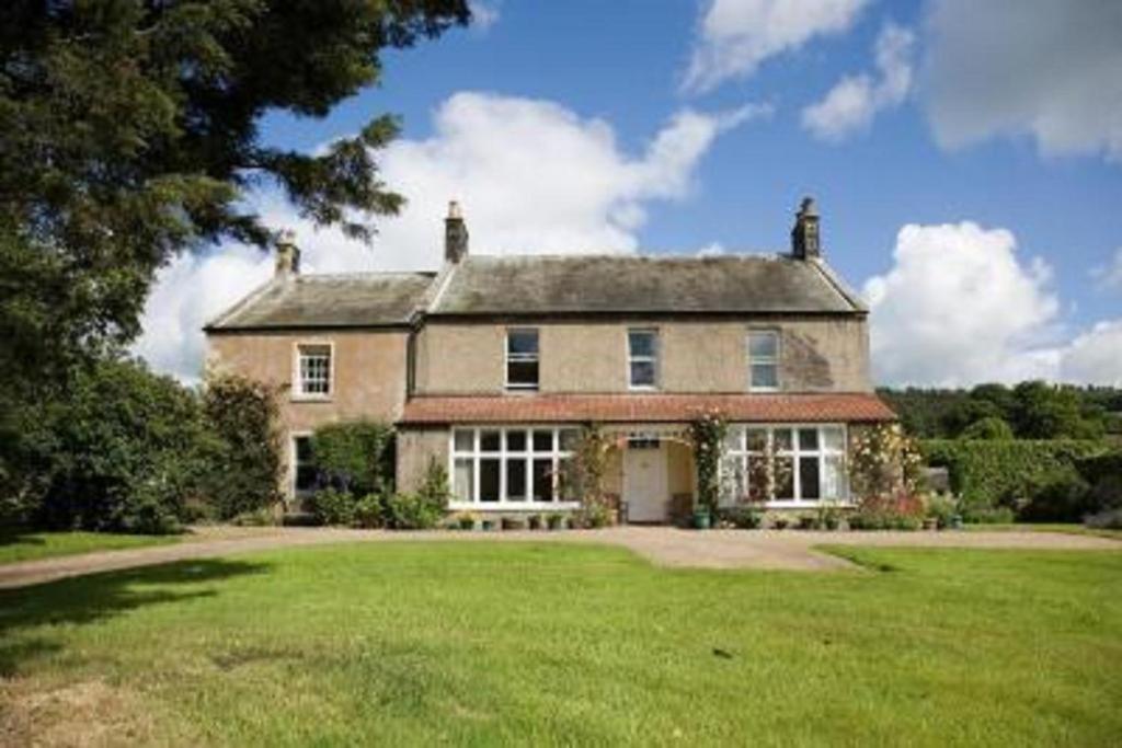 une grande maison avec une grande pelouse devant elle dans l'établissement Anick Grange Farm B&B, à Hexham