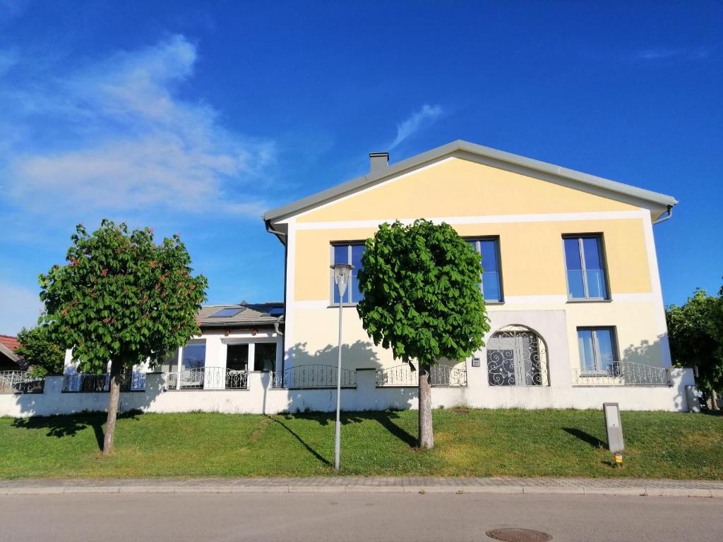 ein Haus mit zwei Bäumen davor in der Unterkunft Campingblick-Gästehaus-Ferienwohnungen in Podersdorf am See