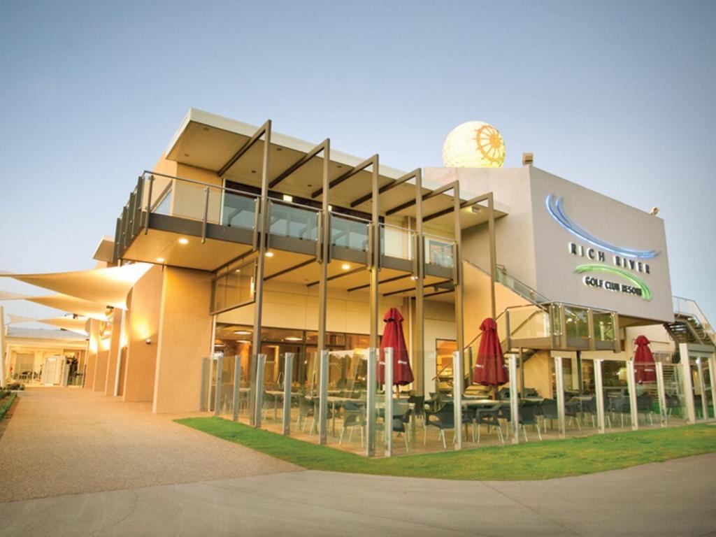 a building with red umbrellas outside of it at Rich River Golf Club in Moama