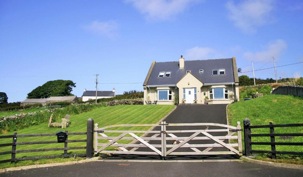 a white house on a hill with a gate at Wild Atlantic View Inishowen in Greencastle