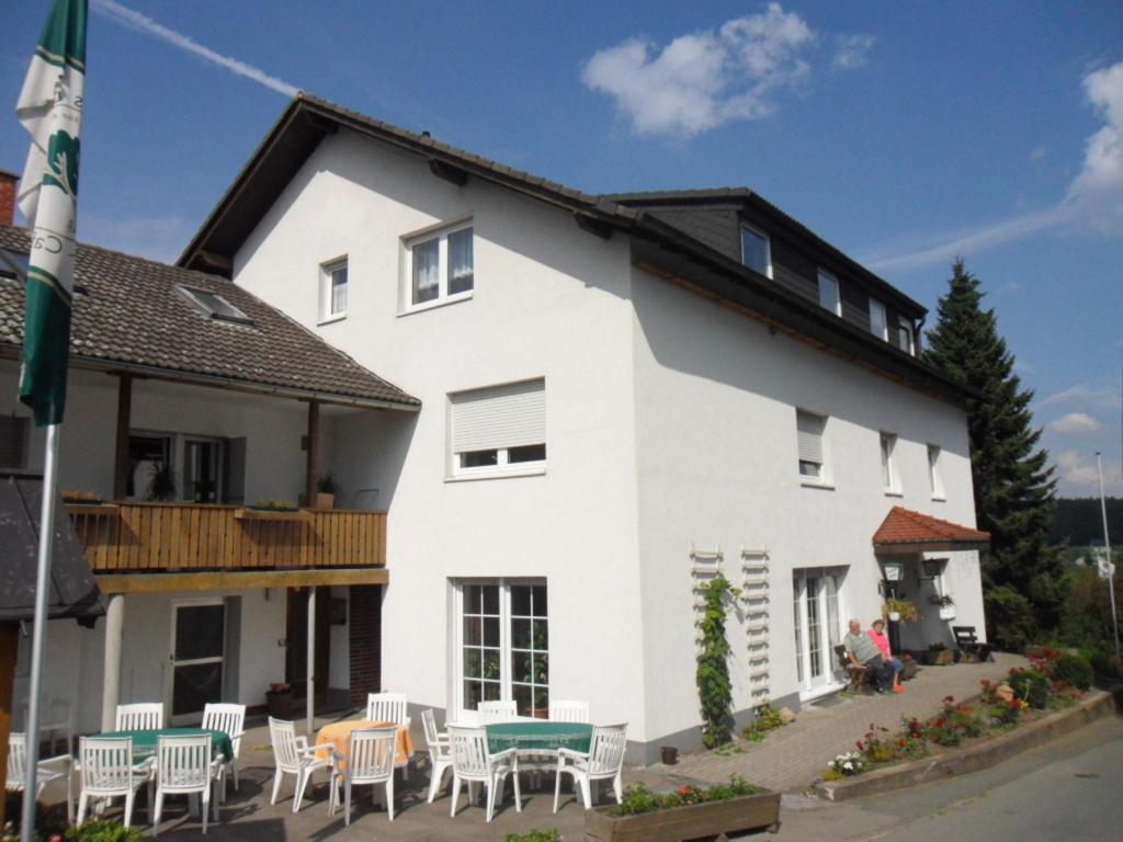 ein weißes Gebäude mit Tischen und Stühlen davor in der Unterkunft Hotel & Pension Haus Dewenter in Lichtenau